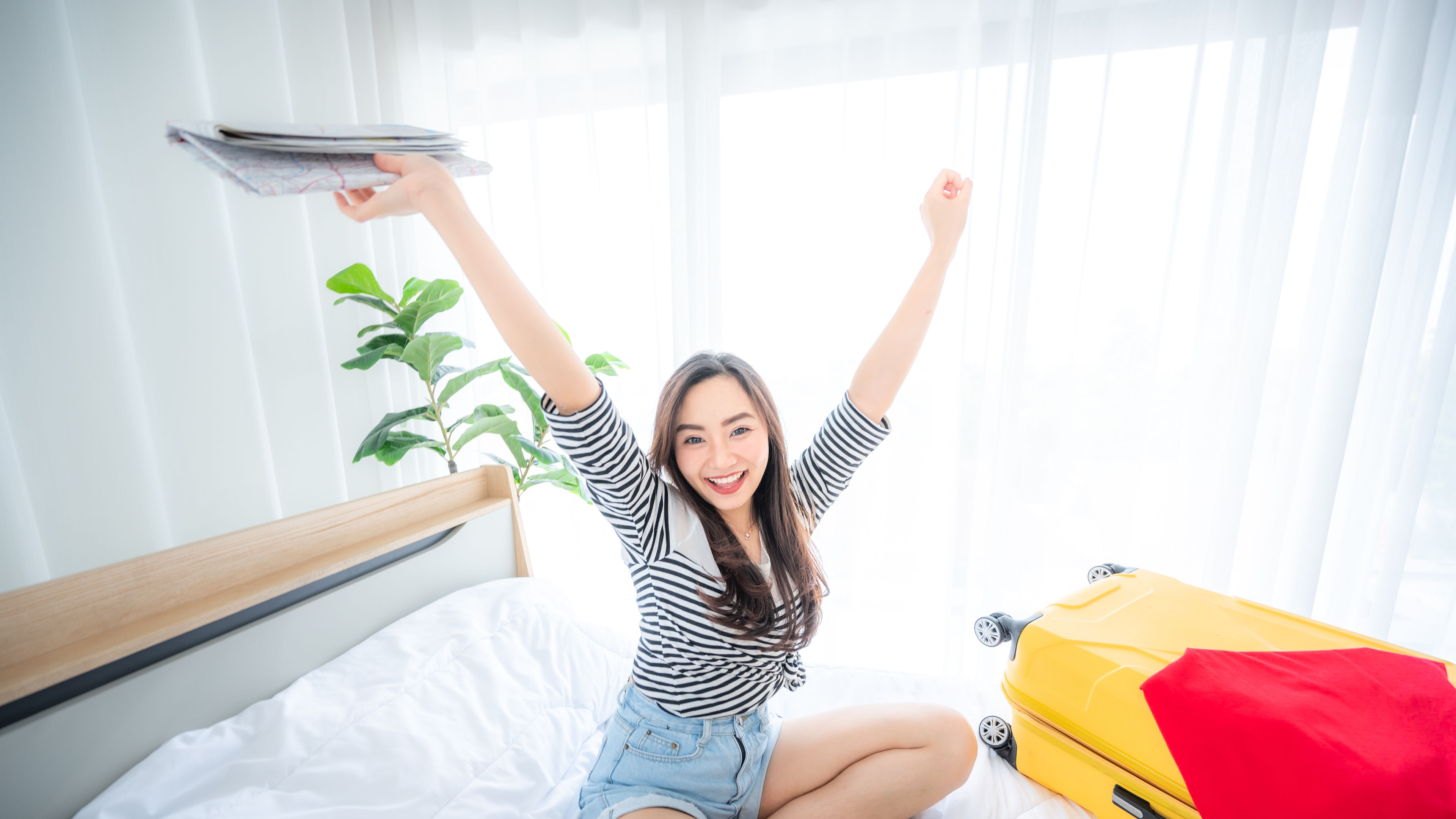 Happy Beautiful Asian woman packing cloth, bikini of the colourful suitcase