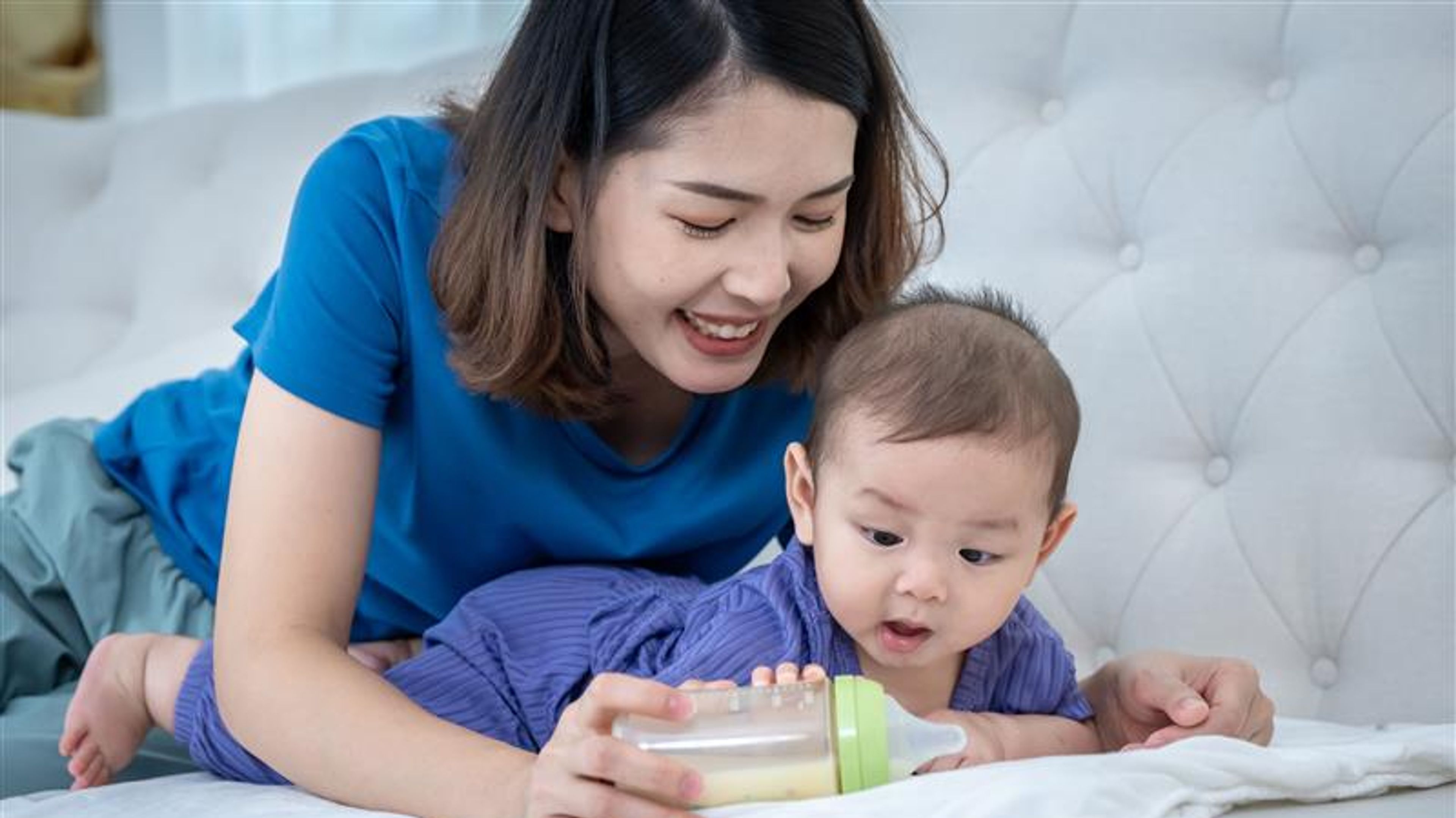 A woman is holding a bottle and child