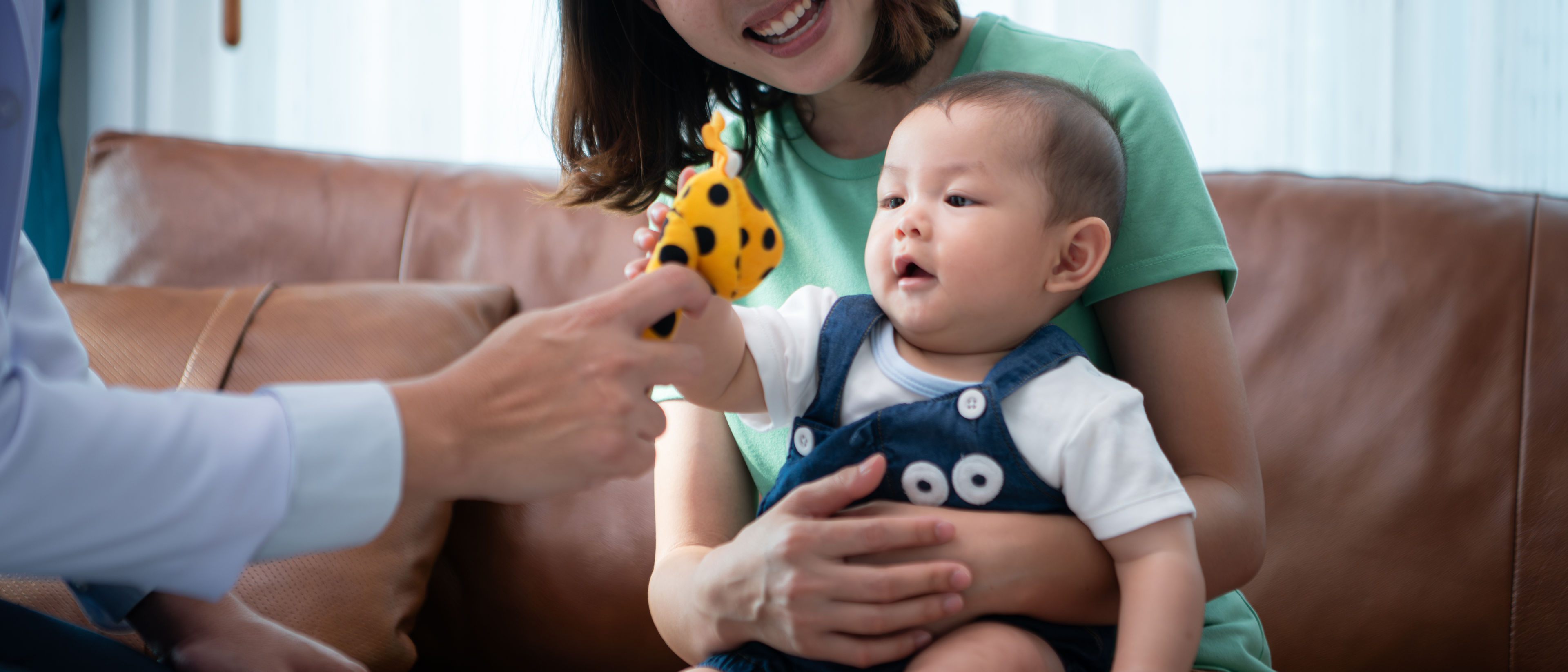Mother sits on a couch holding her baby.