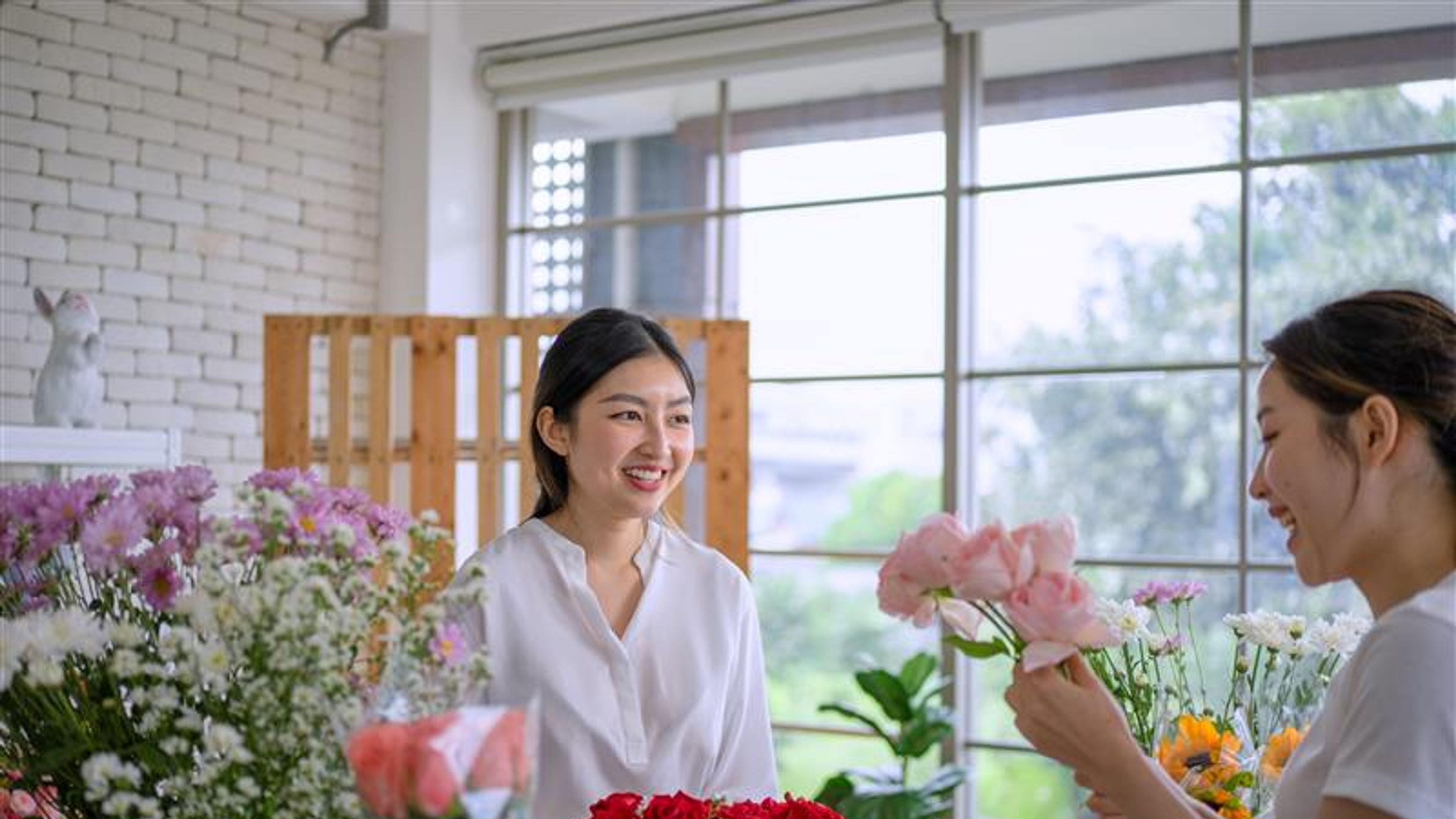 Women holding flowers and smiling at each other