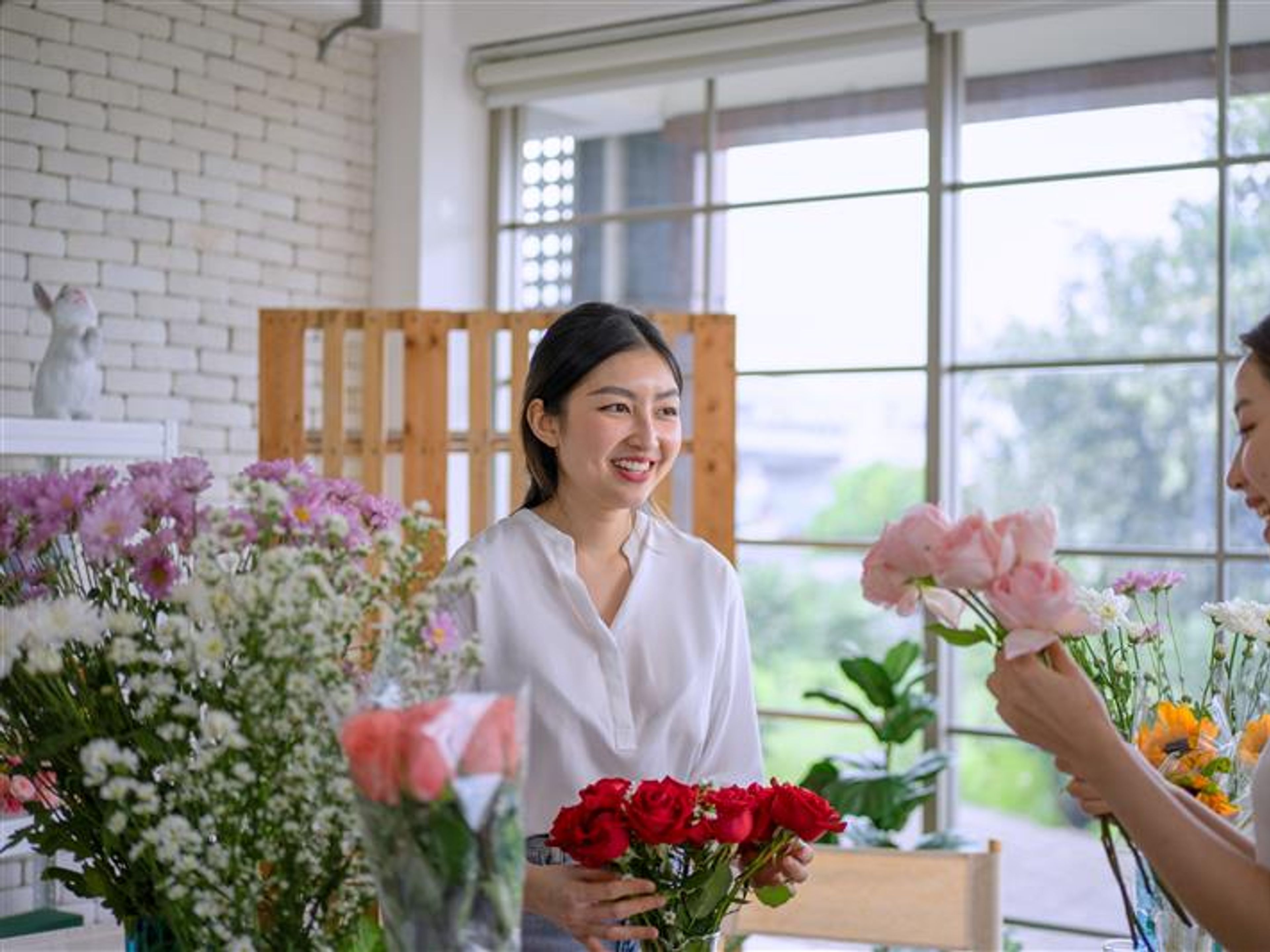 Women holding flowers and smiling at each other